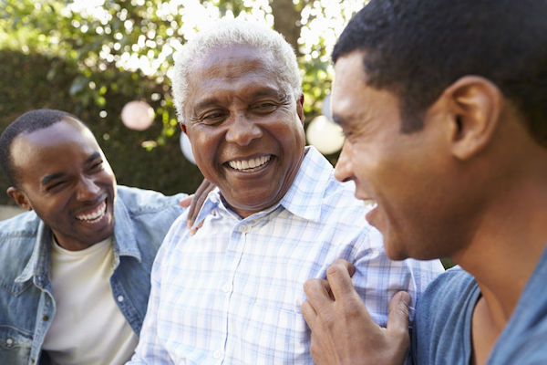 An elderly man laughing with his two sons