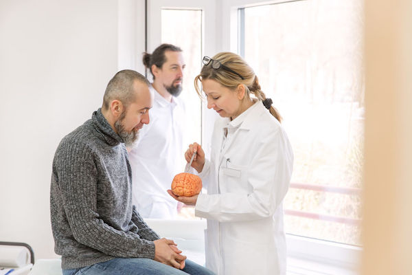 A doctor talking to a patient with a model of a brain