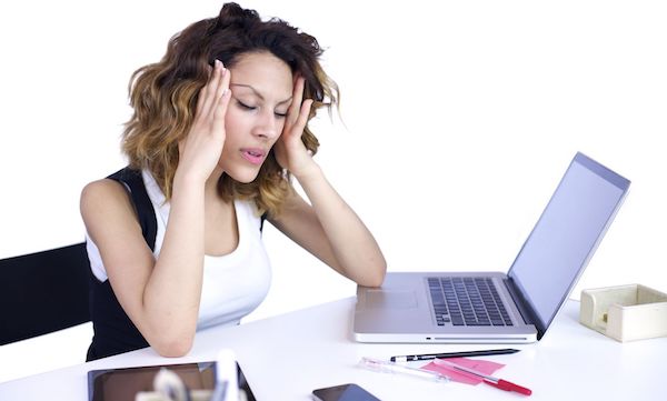 A woman holding her head in her hands at her desk