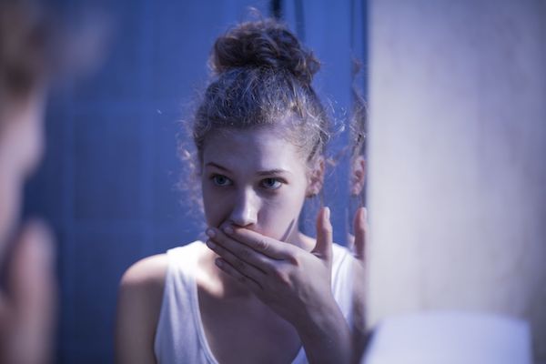 A young woman looking into a bathroom mirror