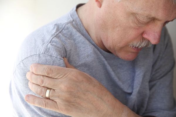 An older man holding his shoulder in pain