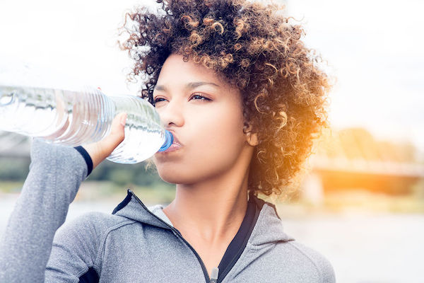 Dehydration A woman drinking water outdoors