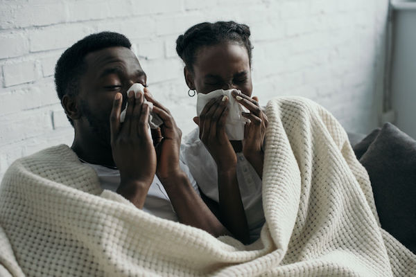 A couple with flu blowing their noses