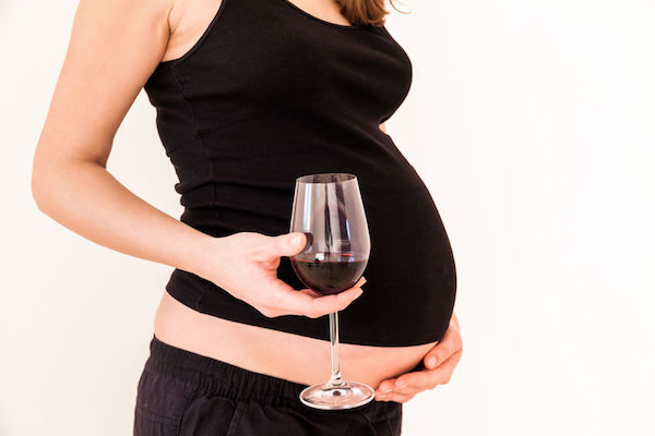 A pregnant woman holding a glass of wine