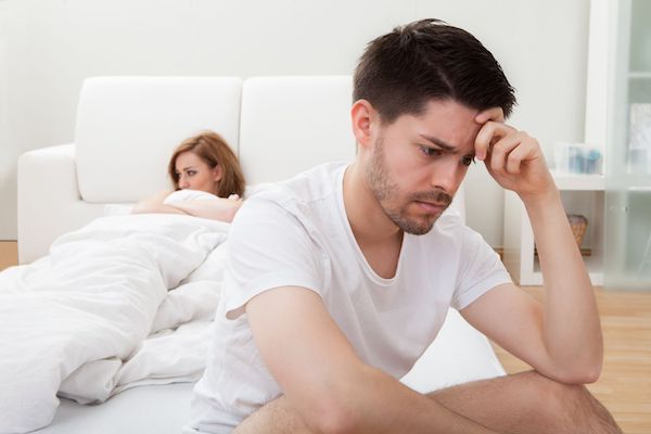 A couple looking worried sitting on a bed