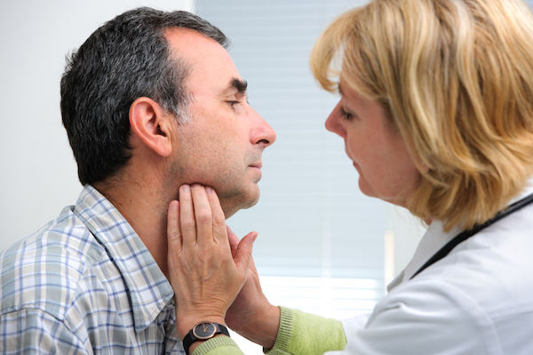 A man having his thyroid examined by a doctor