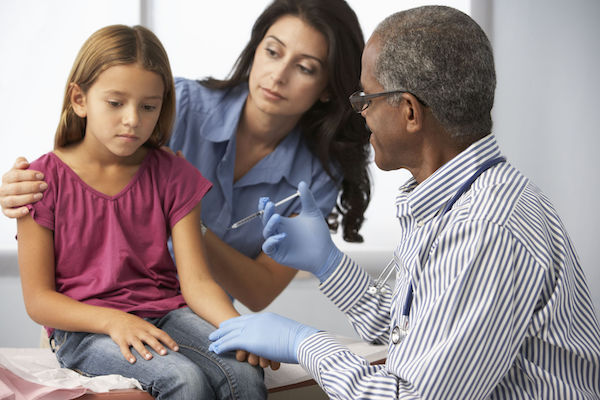 A girl being vaccinated for hepatitis by a doctor