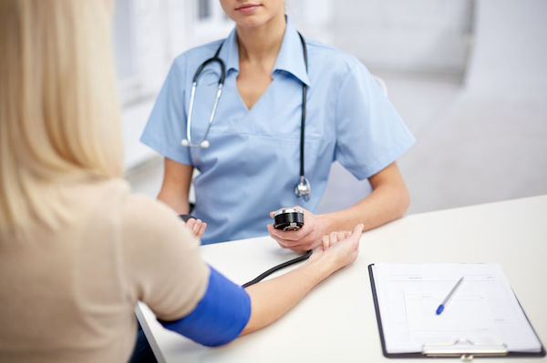 A woman having her blood pressure taken by a nurse