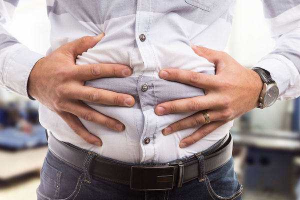 A man clutching his bloated stomach area