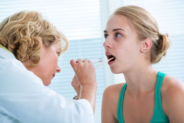 A doctor checking the throat of a female patient